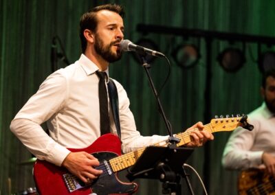 Person playing electric guitar and singing into microphone.