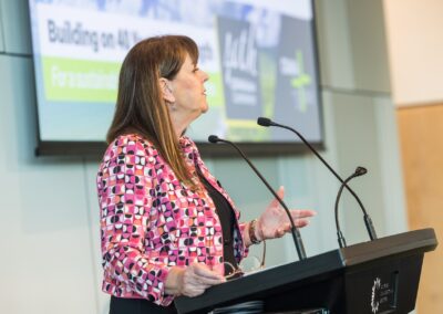 Person stood at a lectern, speaking into microphone.