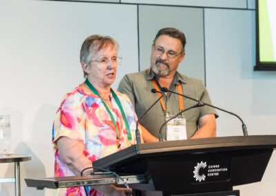 Two people stood at a lectern, speaking into microphone.