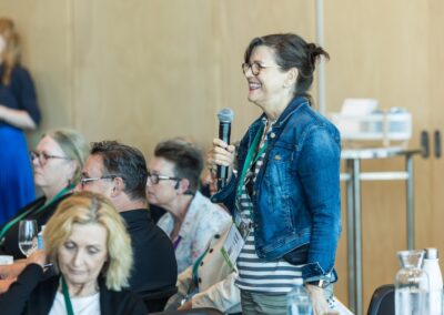 Person stood in audience, talking into a handheld microphone.