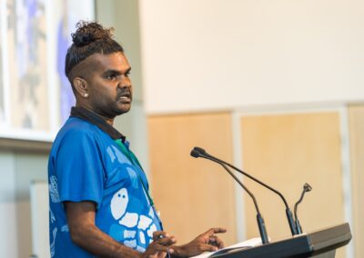 Person stood at a lectern, speaking into microphone.