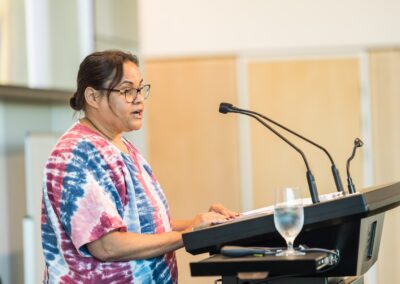 Person stood at a lectern, speaking into microphone.