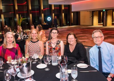 Group of people sat around a circle dinner table, smiling.