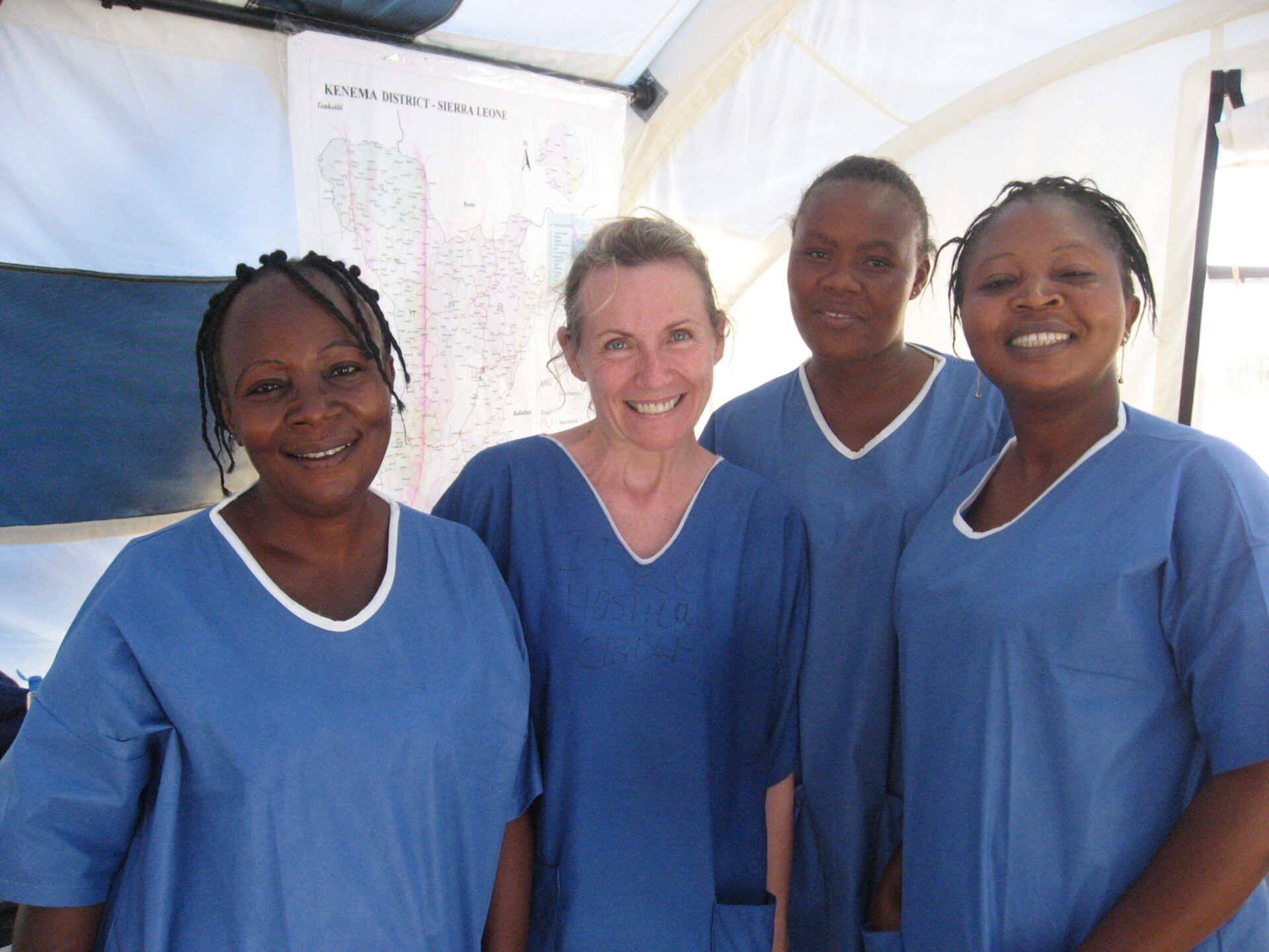 Four people in blue scrubs smiling